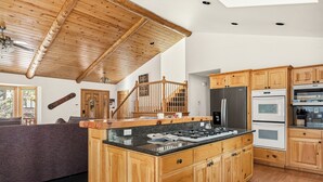 Une cuisine spacieuse dotée de meubles en bois, d’un îlot central et d’un escalier menant à un niveau supérieur.