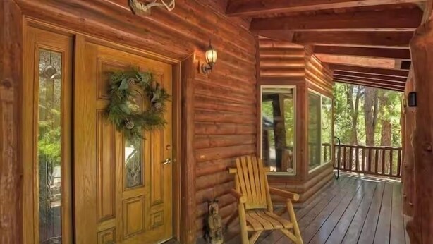 Une cabane en bois avec un porche, une porte ornée d’une guirlande et une chaise.