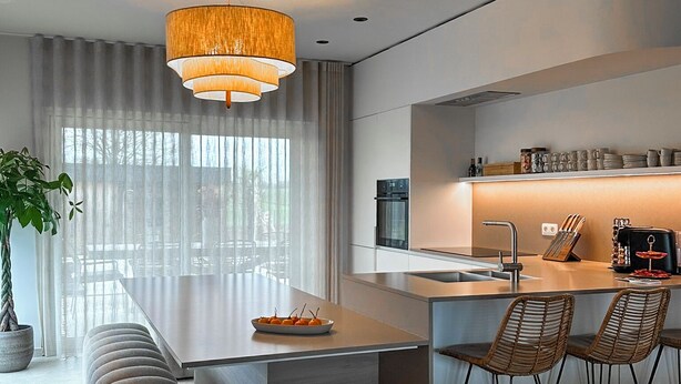 A modern kitchen with a central island, bar stools, and a hanging light fixture. - Inspire Residence and Wellness (Tongeren-Borgloon)