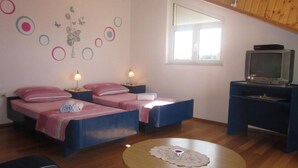 Ein Zimmer mit zwei Betten, einem Fernseher und einem kleinen Tisch mit Unterlage.