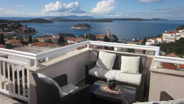 Ein Balkon mit einer Couch, einem kleinen Tisch und einem Blumentopf.