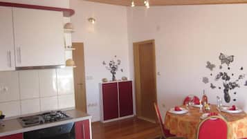 Una cucina con piano cottura, pensili e zona pranzo con tavolo apparecchiato per due.