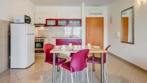 A compact kitchen with a dining area, including a refrigerator, stove, and chairs. - Mise Holiday Apartments - Two bedroom apartment II (Kastel Gomilica)