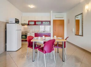 A compact kitchen with a dining area, including a refrigerator, stove, and chairs. - Mise Holiday Apartments - Two bedroom apartment II (Kastel Gomilica)