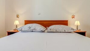 A neatly made bed with two pillows, a wooden headboard, and two bedside lamps. - Mise Holiday Apartments - Two bedroom apartment II (Kastel Gomilica)