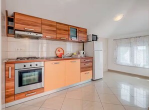 Une cuisine moderne dotée de meubles en bois, d’une cuisinière, d’un four, d’un four à micro-ondes et d’un réfrigérateur.
