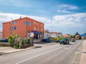 Ein mehrstöckiges Gebäude mit einem Schild für 'auto i moto dijelovi', das eine Kfz-Werkstatt für Autos und Motorräder anzeigt.