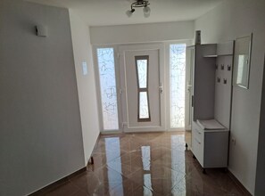 Un couloir avec une porte, un meuble et un sol carrelé.