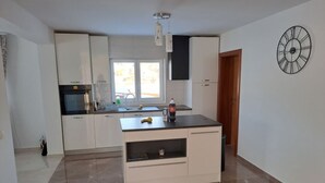 Eine moderne Küche mit weißen Schränken, einer schwarzen Arbeitsplatte und einem eingebauten Backofen.