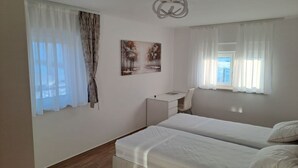 Ein Schlafzimmer mit zwei Betten, einem Schreibtisch und einer Deckenleuchte.