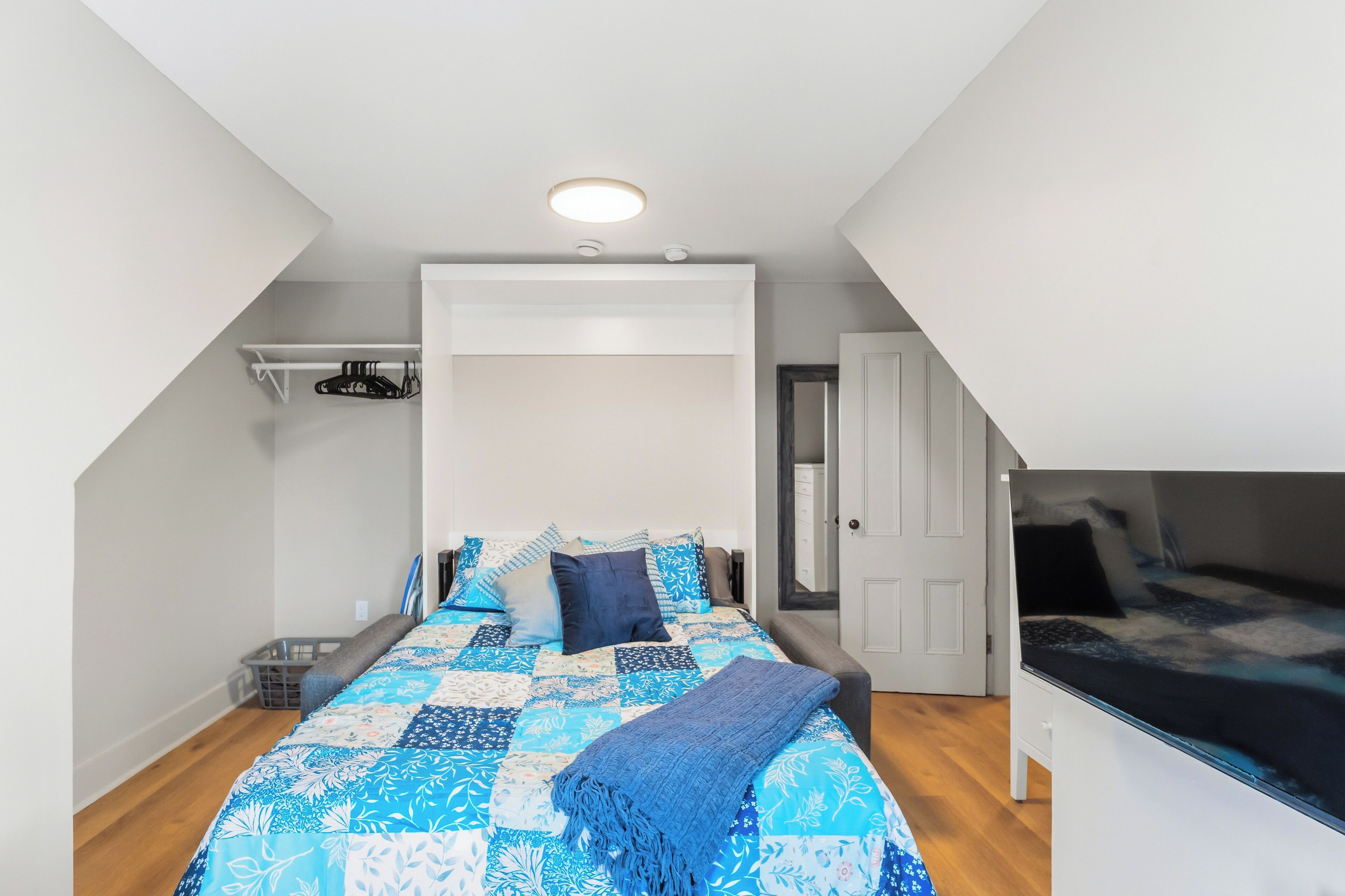 Ein Schlafzimmer mit Bett, Nachttisch, Kleiderschrank und einer Tür.