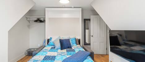 A bedroom with a bed, a bedside table, a wardrobe, and a door.