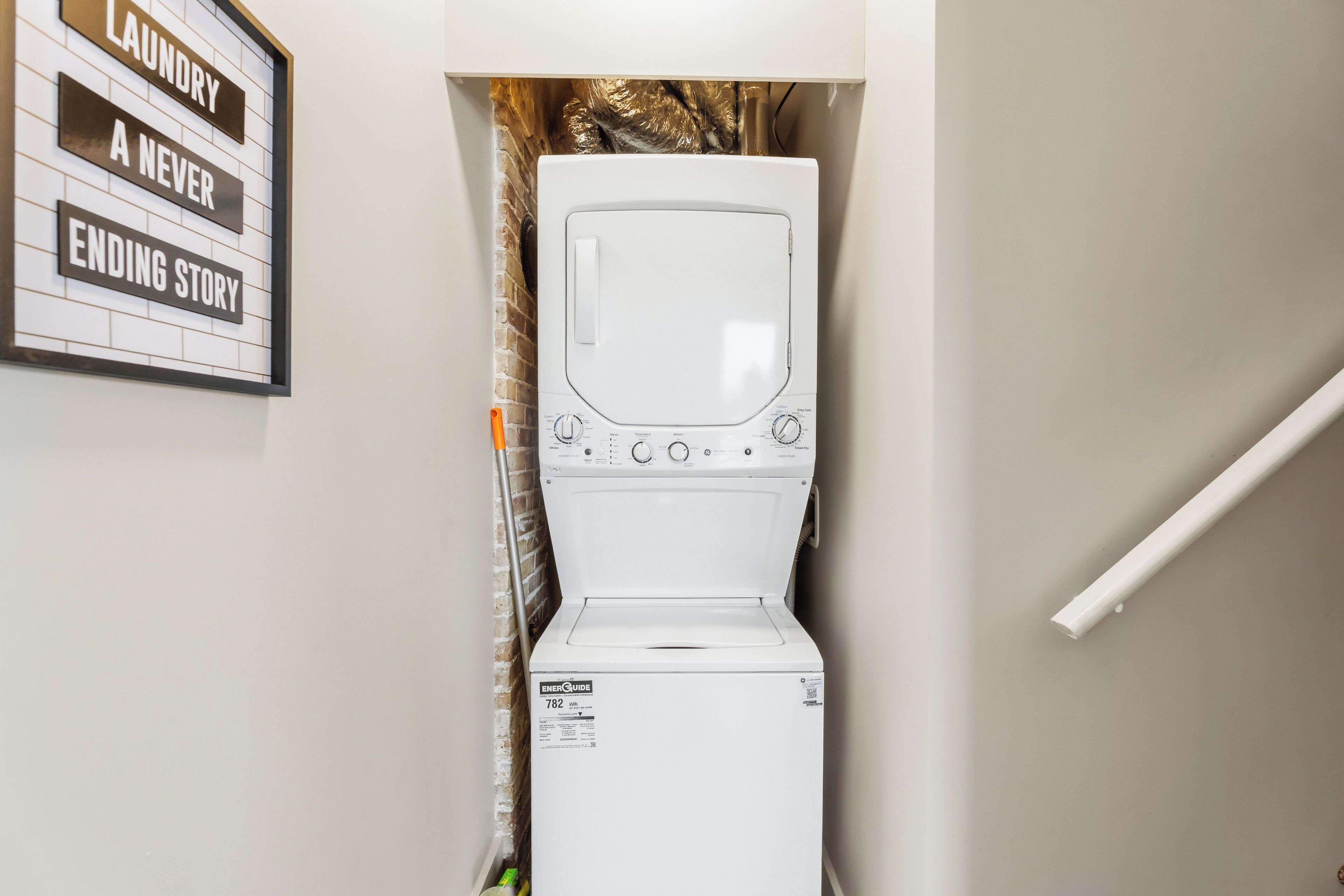 A white washing machine in a laundry room with a sign above it that reads 'Laundry A Never Ending Story.'