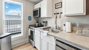 Een moderne keuken met witte kastjes, een roestvrijstalen fornuis, een magnetron en een vaatwasser.