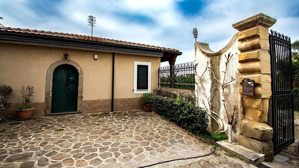 Une cour pavée de pierres, avec un bâtiment doté d’une porte verte et d’une petite fenêtre.