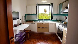 Een kleine keuken met een raam, een kookplaat en een spoelbak.