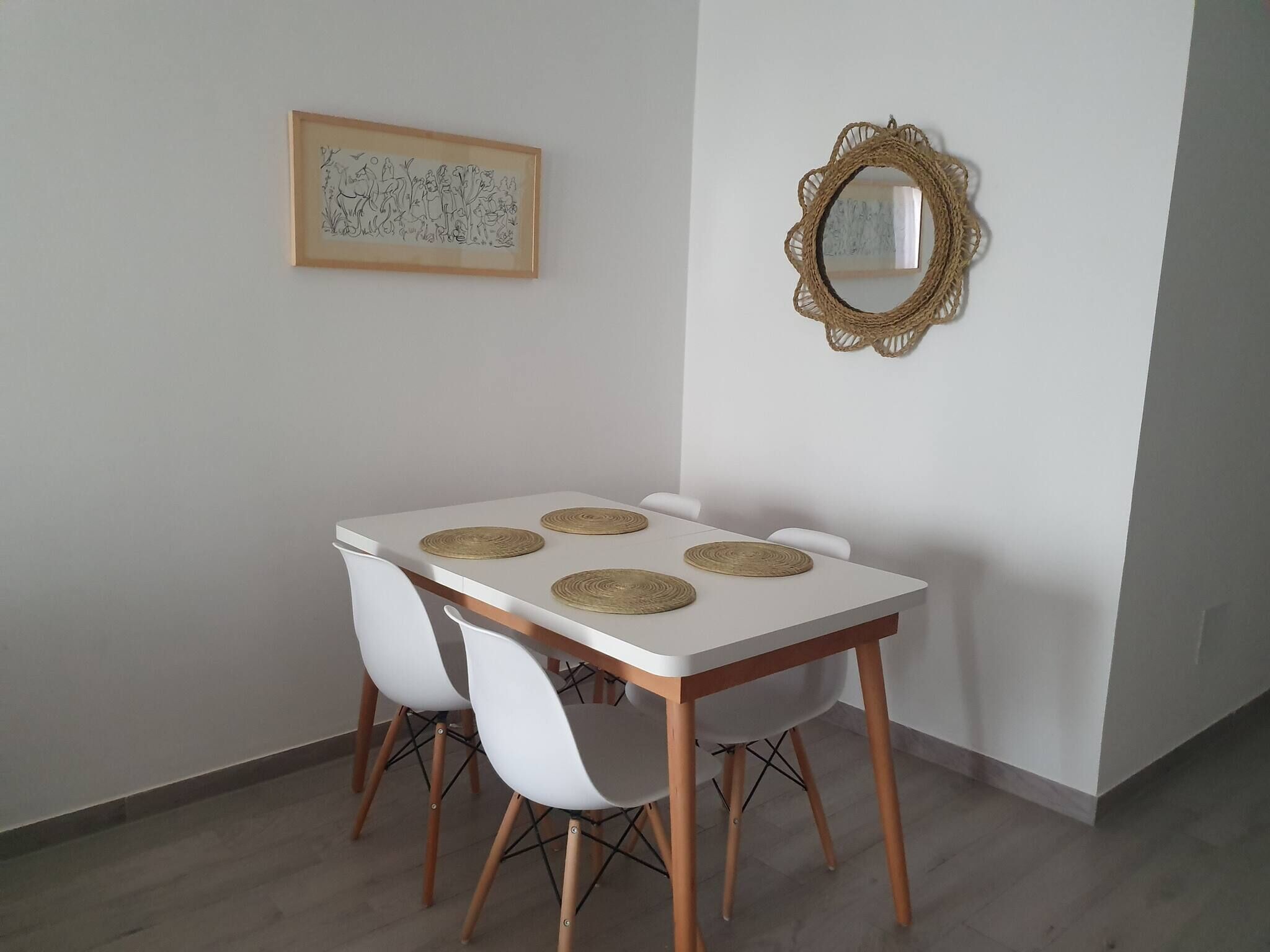 A dining area with a white table, four white chairs, and two woven placemats.
