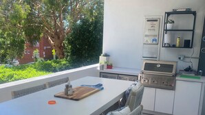Una cucina con un tavolo bianco, sedie di legno, una griglia e un piano cottura a gas Bosch.