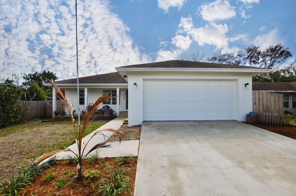 A residential garage with a concrete driveway, a wooden fence, and a clear sky.