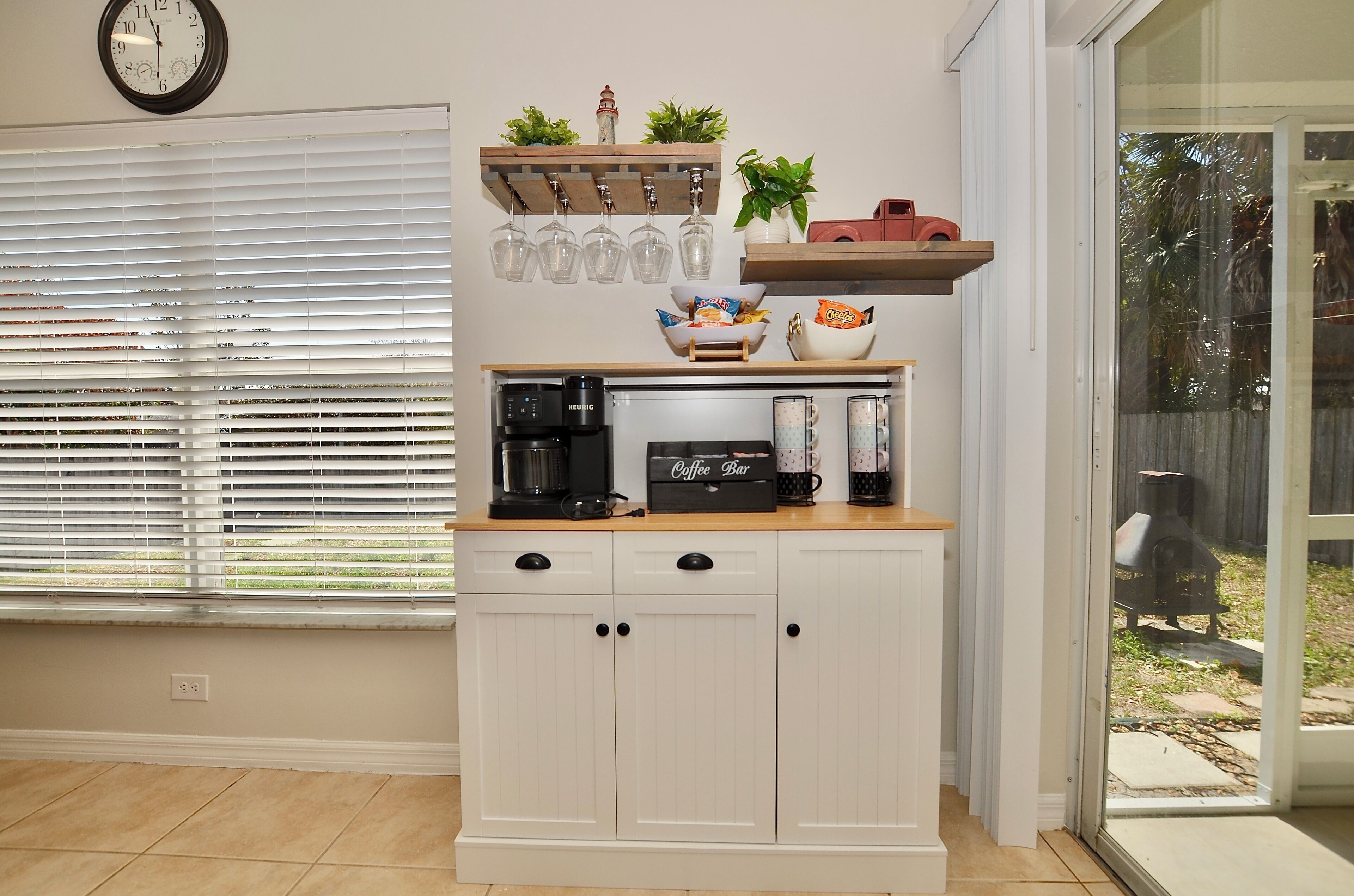 Una cocina con cafetera, barra de café y ventana con persianas.