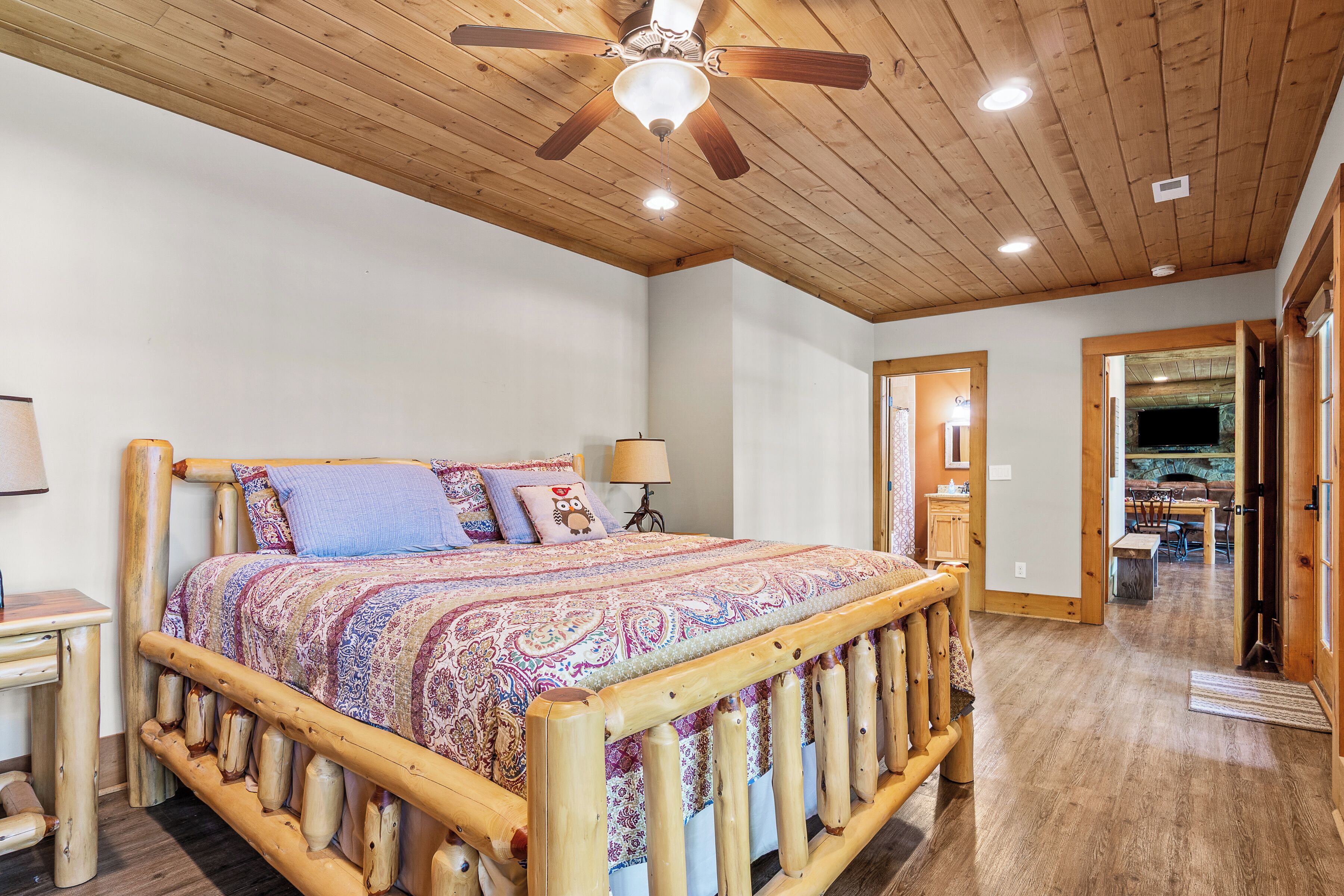 A bedroom with a wooden bed frame, a ceiling fan, and a nightstand.