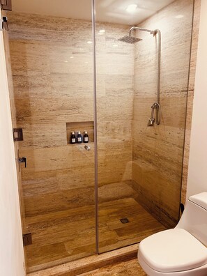 A glass-enclosed shower with a handheld showerhead, a wall-mounted faucet, and a toilet. - MARINA CONDO CORAZON (Cancún)