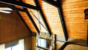 Un plafond en bois avec des poutres apparentes et un mur en pierre.