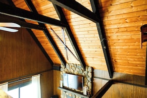 A wooden ceiling with exposed beams and a stone wall.