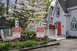 Two reserved parking signs for guests at a property with a white building and a red door.