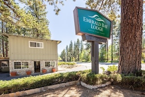 A lodge named 'Emerald Bay Lodge' with a stone facade, a signboard, and a parking area surrounded by trees. - 2 Queen bedroom cabin in South Lake Tahoe w/Full Kitchen and Jetted Bathtub (South Lake Tahoe)