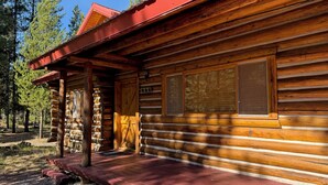 A log cabin with a red roof, wooden siding, and a porch.