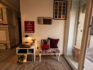 A cozy room with a sofa, a small table with a lamp, a framed picture of vinyl records, and a wall with a motivational quote. - Noonbir Alaçatı (Cesme)