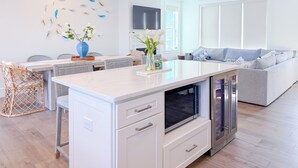Una cucina moderna con isola centrale, elettrodomestici integrati e zona pranzo con sedie in vimini.