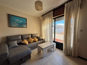 A living room with a sofa, a coffee table, and a painting on the wall. - Golfiño Apartment (O Grove)