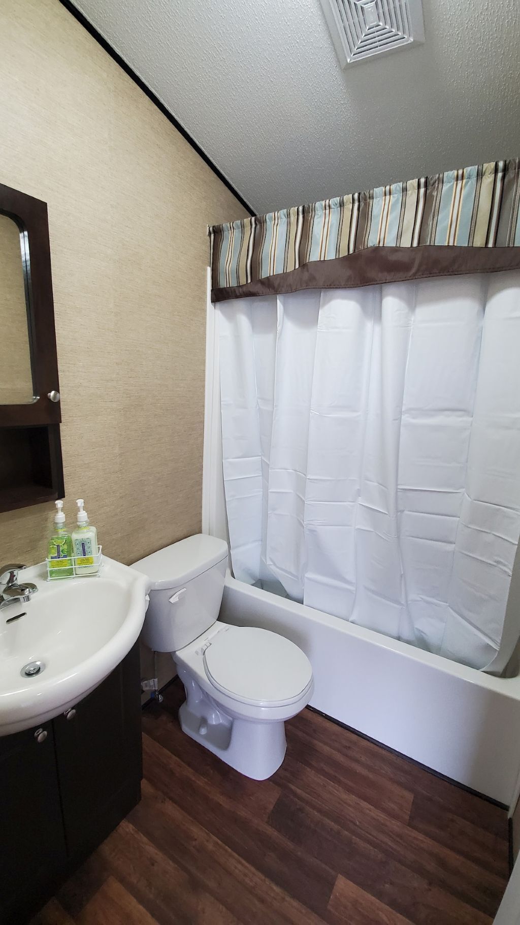 A bathroom with a white toilet, a sink, and a shower curtain.