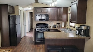 Una cocina equipada con refrigerador, estufa, microondas y cafetera.