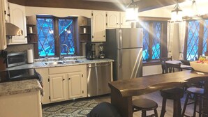 Une cuisine équipée d’un évier, d’une cuisinière, d’un réfrigérateur et de tabourets de bar.