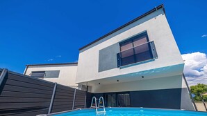 Ein modernes, zweistöckiges Gebäude mit einem Schwimmbecken im Vordergrund.