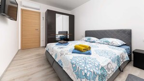 Ein modernes Schlafzimmer mit Bett, Kleiderschrank, Spiegel und Fernseher.