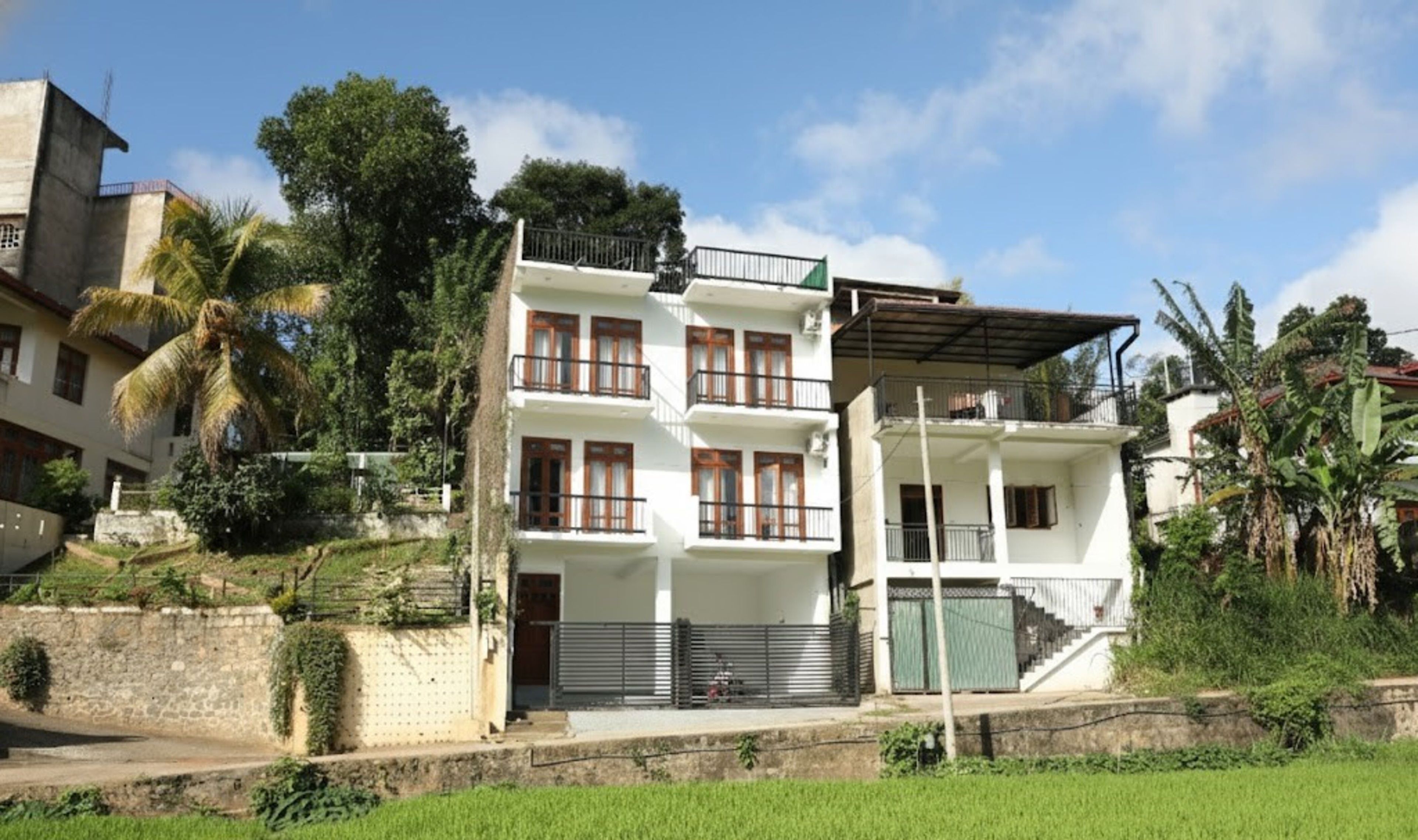 A multi-story residential building with balconies, a gated entrance, and a staircase leading to the upper floors.
