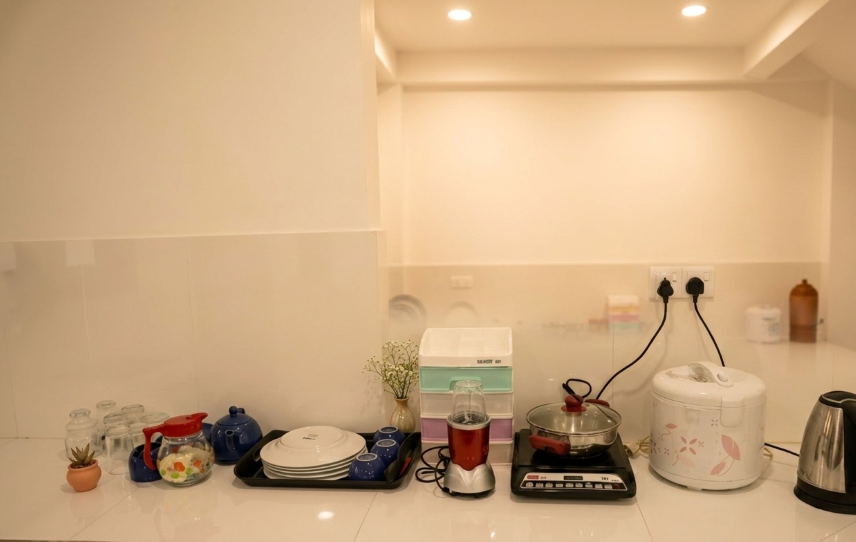 Eine Küche mit diversen Geräten und Kochutensilien, darunter ein Wasserkocher, ein Mixer und eine Kaffeemaschine.
