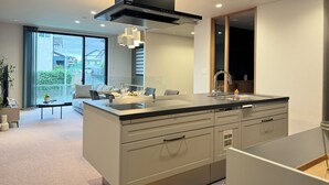 A modern kitchen with a central island, a built-in stove, and a large window.