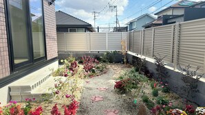 A residential backyard with a gravel garden, various plants, and a brick pathway. - Akikawa Miyoshi 1 | 20 min to TSMC | Entire 3LDK House | Up to 6 Guests (Koshi)