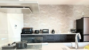Una cocina moderna con microondas, tostadora y tetera sobre la encimera, un lavamanos de acero inoxidable y un ventanal amplio.