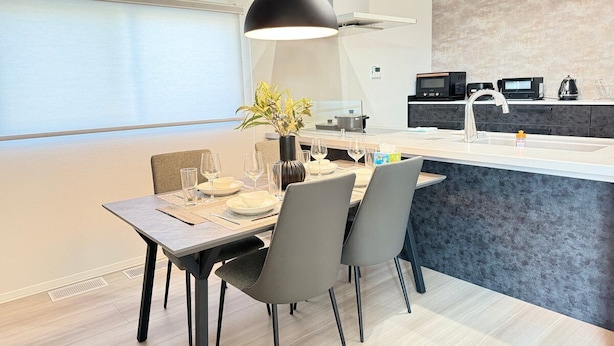 Una cocina moderna con comedor, que cuenta con una isla grande, electrodomésticos contemporáneos y vistas al exterior.