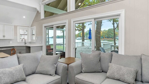 Un interior moderno con techo alto, una zona de cocina y un área de estar con vista al exterior.