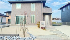 Une maison moderne à deux étages, dotée d’une façade en briques, de grandes fenêtres et d’un petit jardin devant, agrémenté d’un rocail.