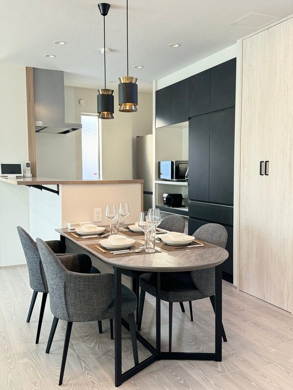 Un área de comedor moderna con una mesa redonda, cuatro sillas grises y un diseño minimalista.