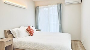 Une chambre à coucher moderne, équipée d’un lit, d’une table de chevet et d’un appareil de climatisation.