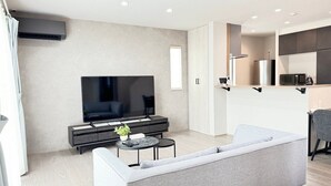Un salon moderne doté d’un téléviseur à écran plat, d’un canapé, d’une table basse et d’un coin cuisine avec un réfrigérateur et un four à micro-ondes.